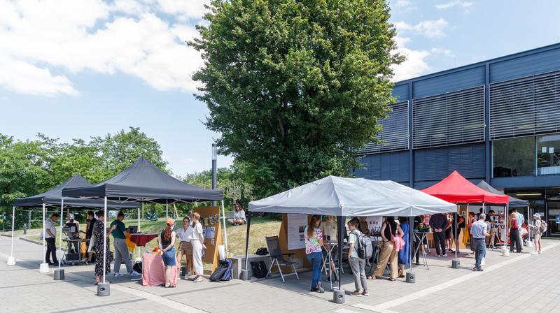 Fünf der über 20 Stände des "Marktes der Möglichkeiten" im Vordergrund der BlueBox. Sie boten spannende Eindrücke zur Forschung rund um die THALES-Projekte. 