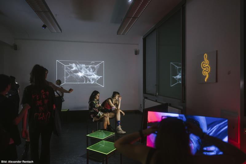 Dunkler Raum mit leuchtenden Ausstellungsobjekten bei der Werkschau 2022