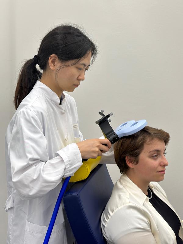 Darstellung der Anwendung der transkraniellen Magnetstimulation. 
