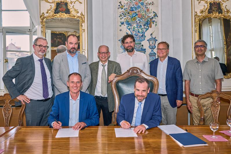 Kai Fischbach (vorne rechts), Präsident der Universität Bamberg, und Stefan Gast, Präsident der Hochschule Coburg (vorne links), unterzeichnen den Kooperationsvertrag.