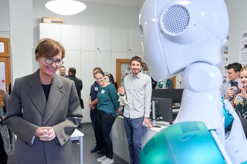 Der am KIT entwickelte humanoide Roboter ARMAR-6 begrüßt Bundesforschungsministerin Bettina Stark-Watzinger (links im Bild) bei ihrem Besuch.