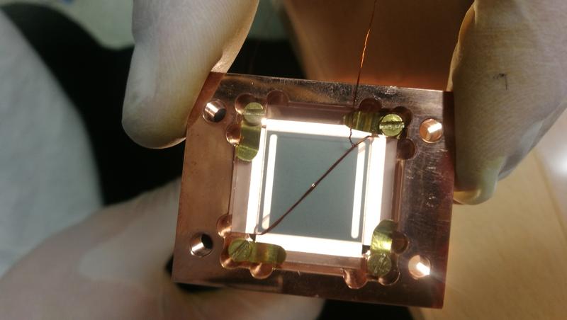 Der Mikrowellen-Resonator besteht aus zwei supraleitenden Chips in einer Sandwich Konfiguration, mit dem kleinen Diamant Steinchen in der Mitte.
