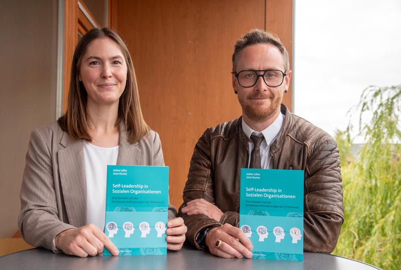 Sozialmanagerin und FH-Alumna Jana Kunze und Prof. Dr. Julian Löhe vom Fachbereich Sozialwesen der FH Münster mit ihrer kürzlich veröffentlichten Erstauflage des Fachbuchs „Self-Leadership in Sozialen Organisationen“. 