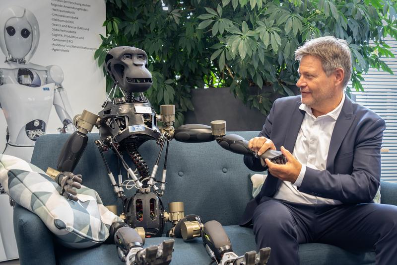 Bundeswirtschaftsminister Robert Habeck mit DFKI-Roboter "Charlie". Im Hintergrund: Roboterdame "AILA"