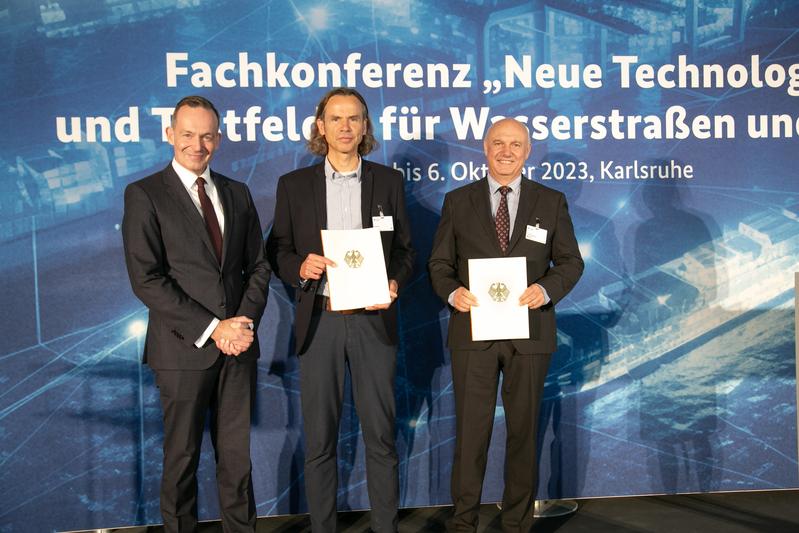 Bundesminister Dr. Volker Wissing übergibt Förderurkunde an Thomas Biebig (Rostocker Hafen, Mitte) und Professor Frank-Hendrik Wurm (Universität Rostock, rechts) 