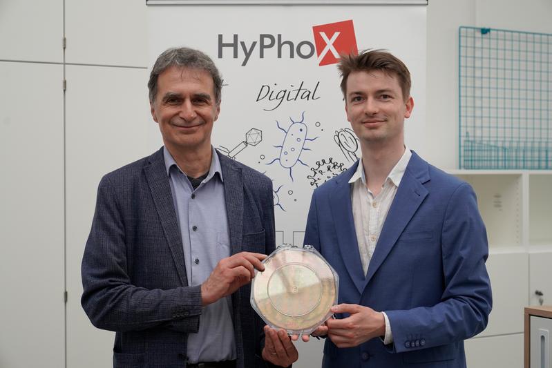 HyPhoX-Gründer Dr. Martin Paul (rechts) und der wissenschaftliche Berater der Ausgründung, Dr. Michael G. Weller von der BAM (links) präsentieren einen neuen Wafer für die Biosensor-Entwicklung. 