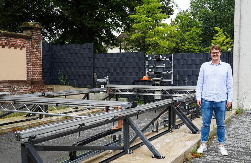 Dr. Christian Meltebrink vor seinem Prüfstand auf dem Gelände des Agro-Technikums der Hochschule Osnabrück. Hinter ihm sind die verschiedenen Sensoren auf der Anlage angebracht.