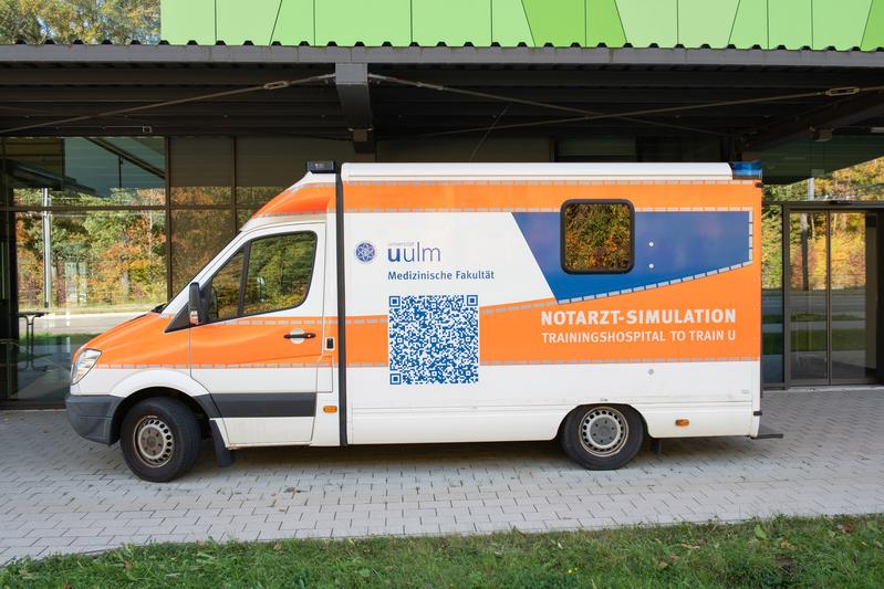 Das Fahrzeug dient als stationärer Übungsraum und steht vor der überdachten Rettungswagen-Zufahrt des Trainingshospitals 