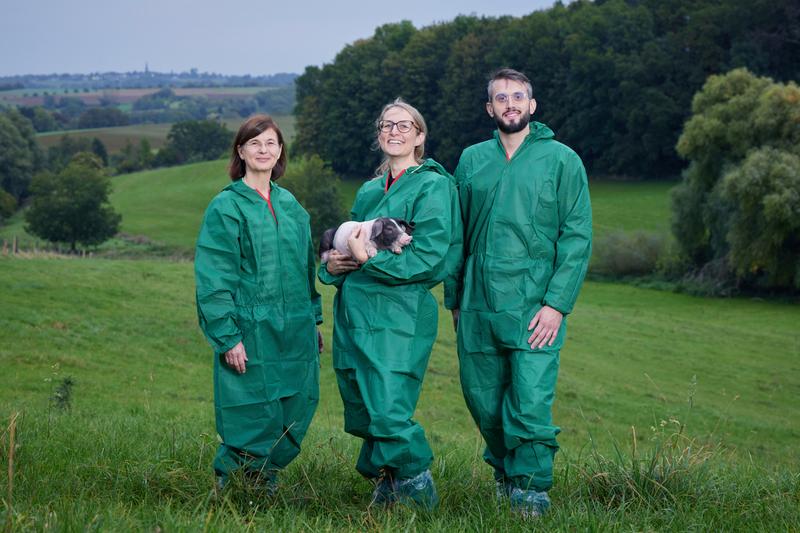 Das Team (von links) in Hygiene-Schutzkleidung und mit Ferkel: Prof. Dr. Monika Hartmann, Jeanette Klink-Lehmann und Milan Tatic auf dem Campus Frankenforst in Vinxel im Siebengebirge. 