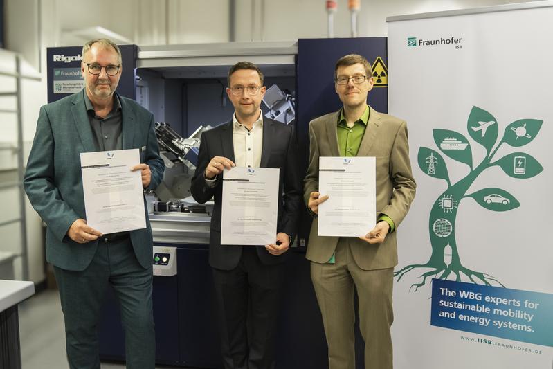 Dr. Michael Hippler, Geschäftsführer der Rigaku Europe SE, Dr. Christian Reimann und Dr. Christian Kranert vom Fraunhofer IISB mit ihren Preisurkunden vor dem Rigaku XRTmicron Röntgentopographiegerät im Center of Expertise for X-ray Topography am IISB.