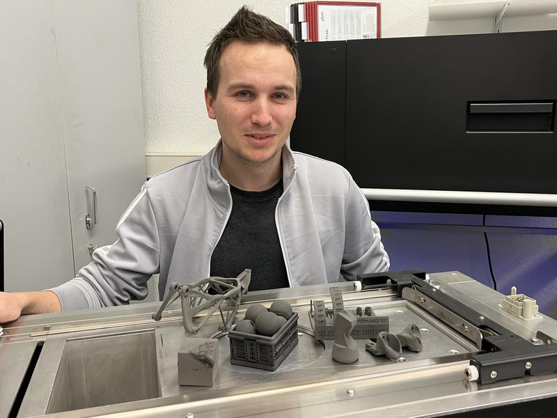 Der Maschinenbau-Ingenieur Erik Westphal vor einer Sammlung von Probe-Werkstücken, die im 3D-Druckverfahren hergestellt wurden.