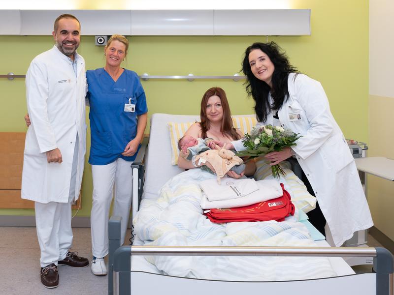 Prof. Cahit Birdir, leitender Oberarzt im Kreißsaal (l.), Schwester Jana (2.v.l.) und Prof. Pauline Wimberger, Direktorin der Klinik für Frauenheilkunde und Geburtshilfe, gratulieren Isabell. Ihr Sohn Finn Karl ist 2023 das 2.000. Baby im Uniklinikum.