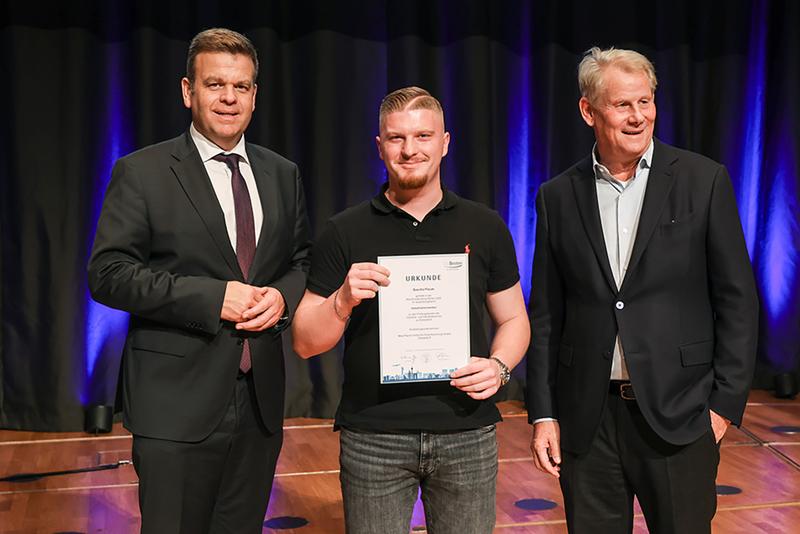 Sascha Flaum mit Matthias Heidmeier, Staatssekretär im NRW-Ministerium für Arbeit, Gesundheit und Soziales (links), und IHK Präsidenten Andreas Schmitz (rechts) bei der IHK Besten-Ehrung 2023.