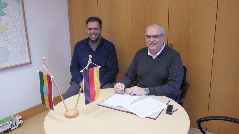 Rector Prof Dr Dr hc. Bastian Kaiser signing the MOU while Prof. Dr Abele looks on.