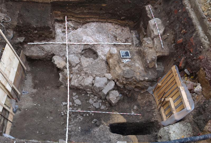 Blick von Osten auf die Grabungsfläche. Im Zentrum die Reste des halbmondförmig gebogenen ottonenzeitlichen Mauerzuges, an den zum oberen Bildrand hin ein Sockel aus Gipsmörtel anschließt. 