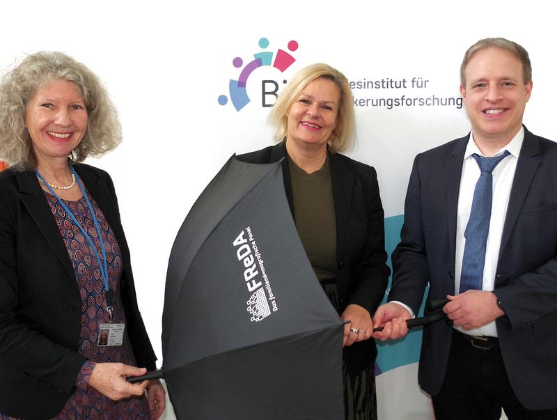 Bundesinnenministerin Nancy Faeser bekommt als Schirmherrin des FReDA-Datenprojekts von Prof. Dr. C. Katharina Spieß (li.) und Prof. Dr. Martin Bujard symbolisch einen Schirm überreicht.