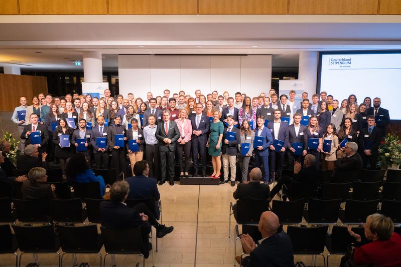 Die Deutschlandstipendiat*innen der Frankfurt UAS des Jahrgangs 2023/24 mit Dr. Ingo Wiedemeier (Mitte l.), Prof. Dr. Kai-Oliver Schocke (Podium M.) sowie Astrid Kramer (Podium r.) und Ursula Klein (Podium l.) von der Hochschulförderung der Frankfurt UAS.