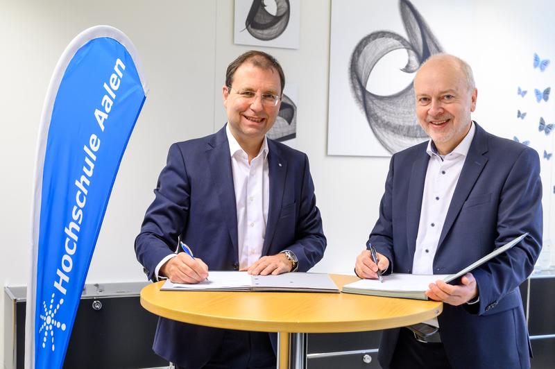 Richard Bannmüller, Vorsitzender Geschäftsführer der Trumpf Laser und Systemtechnik GmbH, und Hochschulrektor Prof. Dr. Harald Riegel (rechts) beim Unterzeichnen des Kooperationsvertrags.
