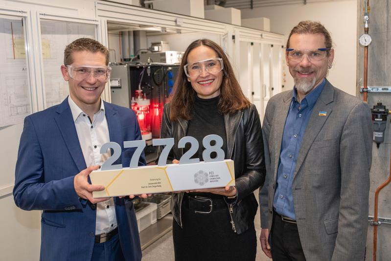 Prof. Dirk Ziegenbalg (links) erhält aus den Händen von Stefanie Jordan (Teva Pharmaceuticals) und Dr. Tobias Pacher (Chemie.BW) symbolisch eine Förderung des Fonds der Chemischen Industrie (FCI)