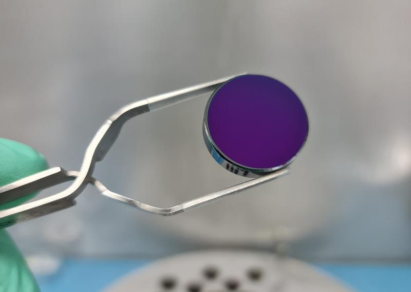 Ein Foto des Siliziumsubstrat mit einem Durchmesser von 25 mm, wie es für die Superspiegel verwendet wurde. Die bereits aufgebrachte herkömmliche Basisbeschichtung erzeugt einen violetten Farbeindruck.