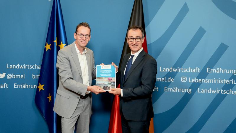 Bundesminister Cem Özdemir (r.) nimmt am 8. Dezember 2023 das aktuelle Gutachten des Wissenschaftlichen Beirats für Agrarpolitik, Ernährung und gesundheitlichen Verbraucherschutz (WBAE) aus der Hand des Beiratsvorsitzenden Prof. Dr. Achim Spiller entgegen