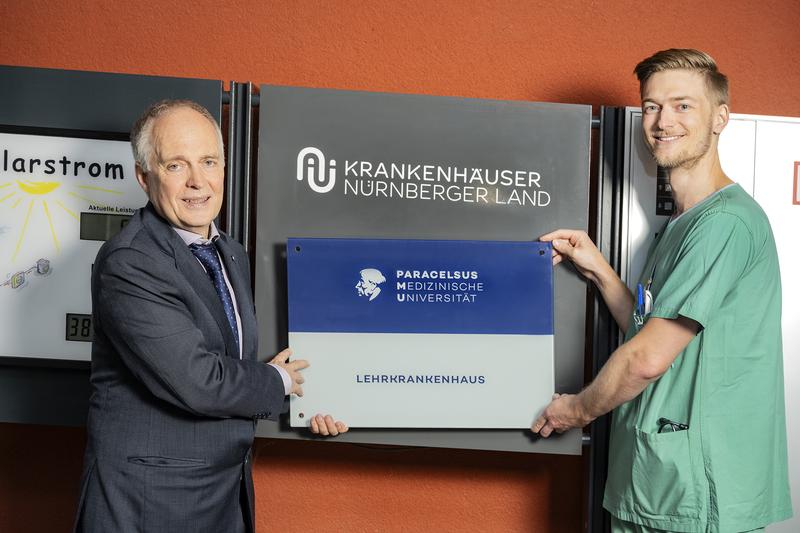  PMU-Vizerektor Prof. Dr. Theodor Fischlein (li.) und Assistenzarzt Dr. Maximilian Haupt mit dem  neuen Lehrkrankenhaus-Schild vor dem Krankenhaus Lauf.