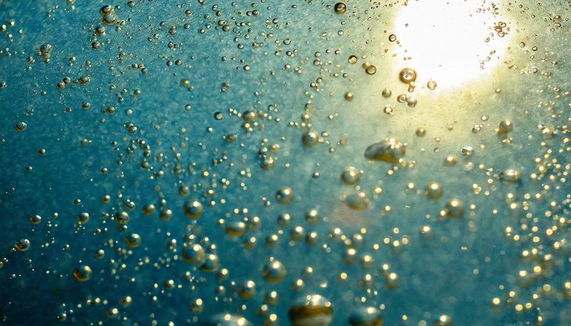Im neuen Verfahren wird Luft durch eine Flüssigkeit geleitet. Wird die Flüssigkeit mit Licht bestrahlt, wird das Treibhausgas CO2 wieder freigesetzt und kann aufgefangen werden (KI-​generiertes Symbolbild). 