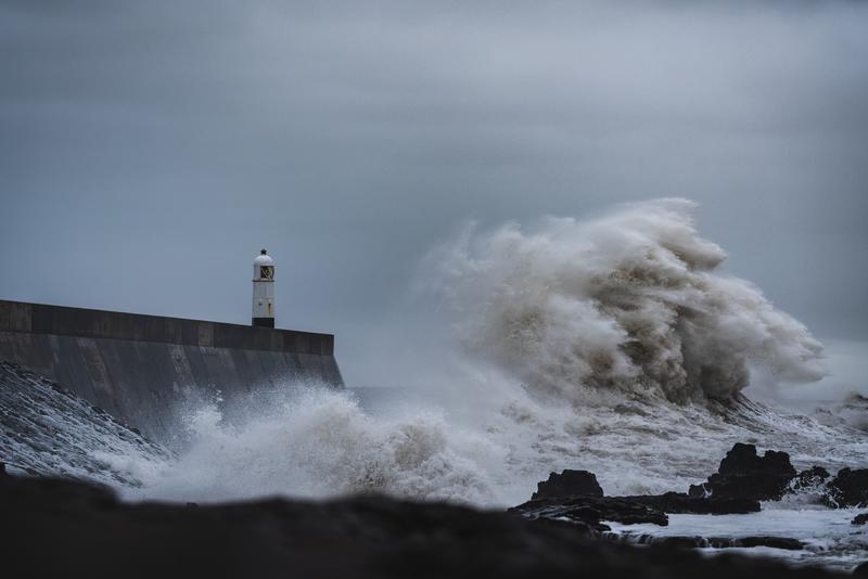 Küstengebiete und -Gesellschaften sind zunehmend marinen Naturgefahren und Extremereignissen ausgesetzt - hier treffen stürmische Meereswellen eine Küste mit Leuchtturm