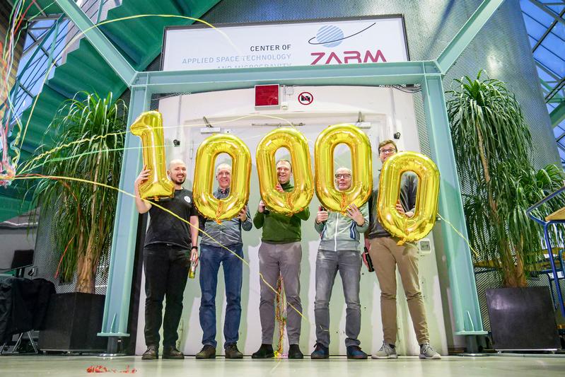 Wissenschaftler und Fallturm-Ingenieure, die beim 10.000sten Experiment dabei waren, feiern den Meilenstein.