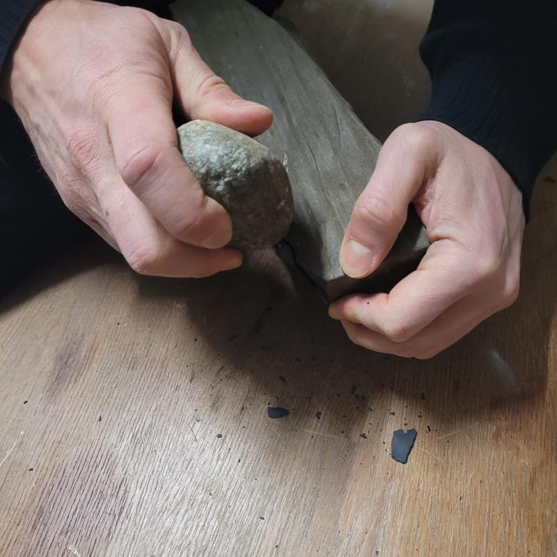 Der Forscher Patrick Schmidt stellt ein Steinwerkzeug aus südafrikanischen Rohmaterialien durch Zuschlagen her.
