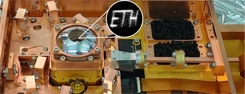 Durch Bewegen eines einzelnen gefangenen Ions in einer zweidimensionalen Ebene und Beleuchten mit einem Laserstrahl kann das ETH-​Logo erzeugt werden. Das Bild kam durch Mittelwertbildung über viele Wiederholungen der Transportsequenz zustande.