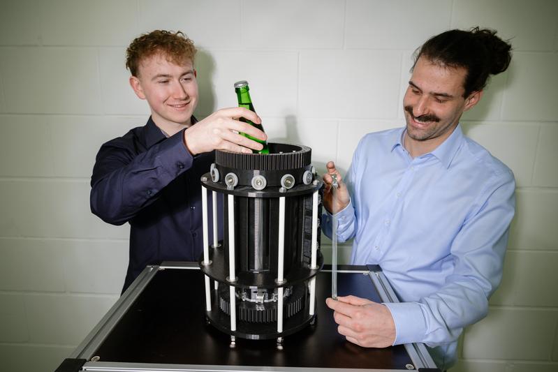 Eine kleine Flasche hat Platz im ersten Mini-Kühlschrank mit künstlichen Muskeln. Student Nicolas Scherer (l.) und Doktorand Lukas Ehl (r.) forschen im Team der Professoren Stefan Seelecke und Paul Motzki am neuen Kühlsystem.