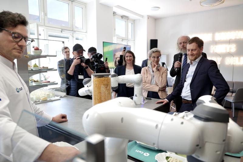 CeTIBAR: Ministerpräsident Michael Kretschmer, TUD-Rektorin Prof.in Ursula M. Staudinger und Sprecher des CeTI-Exzellenzclusters Prof. Frank H.P. Fitzek bei der Eröffnung der "Roboterküche" mit Starkoch Benjamin Biedlingmaier.