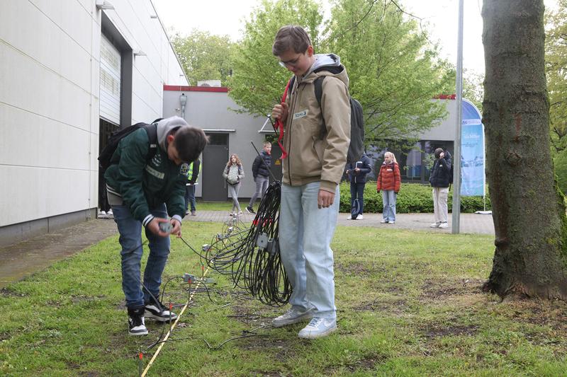 Schüler bauen eine kleine geoelektrische Messstrecke auf, um die elektrische Leitfähigkeit des Untergrunds zu bestimmen.