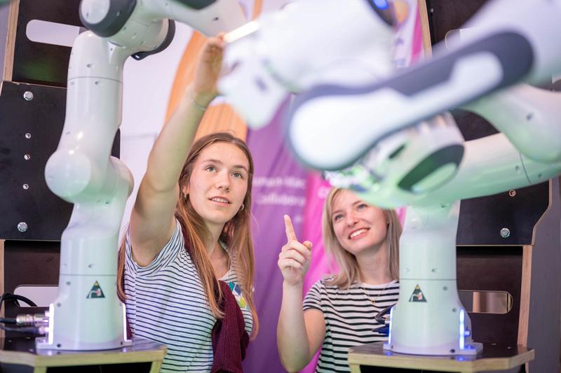 Two young women look at robots