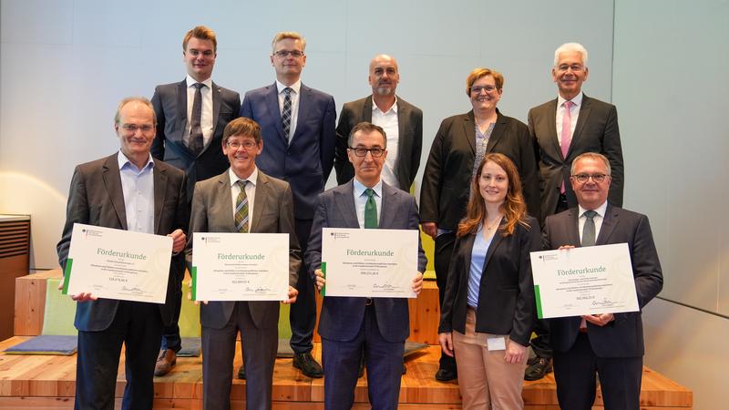 Bundesminister Cem Özdemir (unten, 3.v.l.) überreicht die symbolischen Förderbescheide an die Projektbeteiligten. 