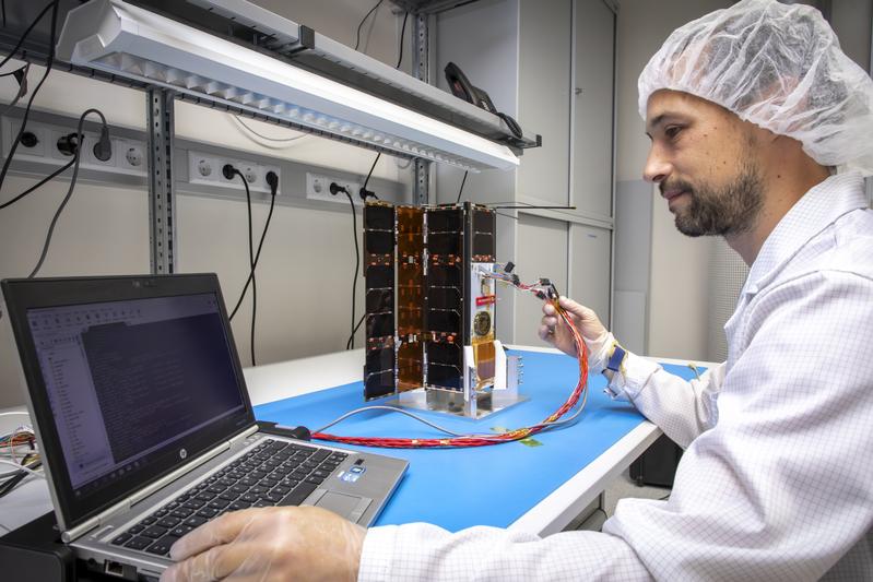 Maximilian Henkel vom Institut für Kommunikationsnetze und Satellitenkommunikation im Jahr 2019 beim Konfigurieren des Satelliten im Reinraum der TU Graz.