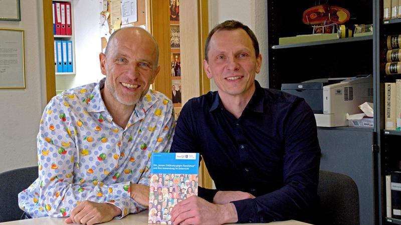 Die Jenaer Biologiedidaktiker Professor Uwe Hoßfeld (l.) und Dr. Karl Porges mit einer der zahlreichen Publikationen zur Jenaer Erklärung, wofür sie mit dem Thüringer Demokratiepreis 2024 ausgezeichnet wurden.