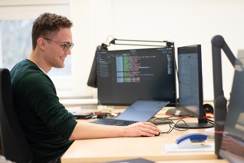 Forscher sitzt an einem Schreibtisch mit mehreren Monitoren.