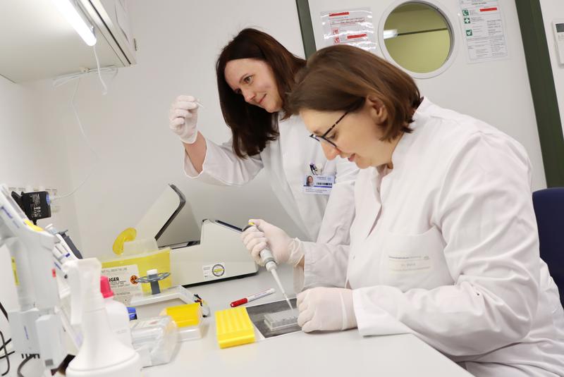 Die medizinische technische Assistentin Inge Reck (vorn) aus dem Team von Heike Weber (hinten) pipettiert hier eine PCR (Polymerase-Kettenreaktion). Bei der PCR werden kurze genau definierte Genregionen vermehrt.