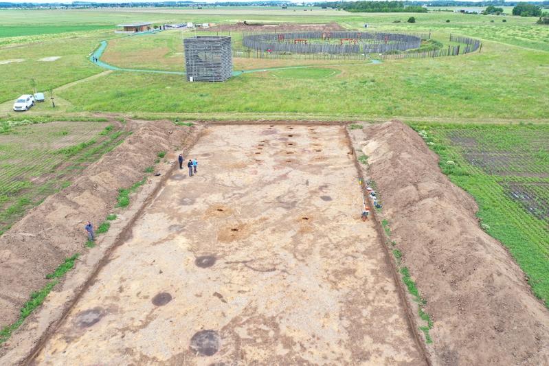 Der größte der drei neu entdeckten Hausgrundrisse der Glockenbecherkultur (ungefähr 2450 bis 2250 vor Christus) mit dem Ringheiligtum im Hintergrund, Blick nach Westen. Maße des Gebäudes: 19,75 Meter (Länge) mal 7,35 Meter (maximale Breite).