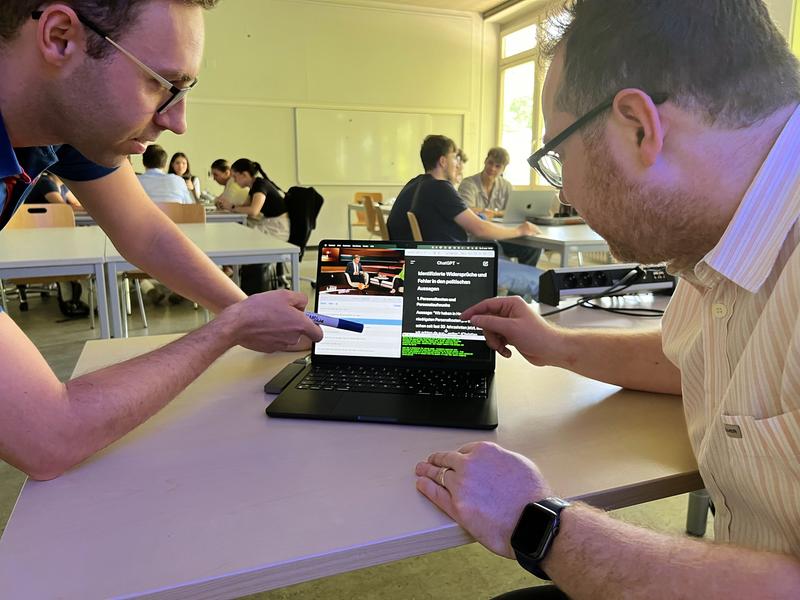 Werfen einen Blick auf den KI-Faktencheck-Prototyp: Dozent Rafael Bujotzek, rechts, mit Student Simon Kirschner