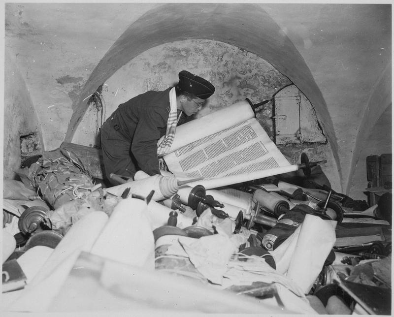 Im Keller des Instituts zur Erforschung der Judenfrage: Kaplan Samuel Blinder sichtet vom Einsatzstab Reichsleiter Rosenberg geraubte Thorarollen, 6. Juli 1945.