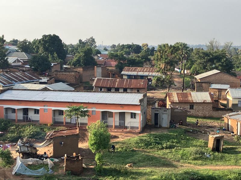 Ortsansässige Bevölkerung in der Stadt Arua, Uganda. Eine Person links unten im Bild bereitet Essen mit einer improvisierten Kochlösung zu. 