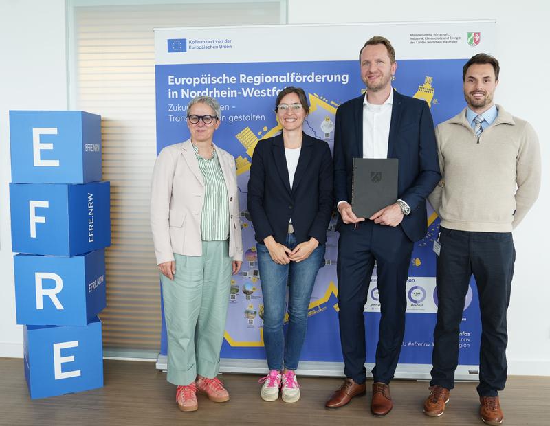 Startschuss für GenISys: Das Projektteam bekam den Zuwendungsbescheid persönlich von Staatssekretärin Silke Krebs (li., MWIKE NRW) überreicht. Dr.-Ing. Richard Meyes (re., Bergische Universität Wuppertal) vertrat dabei Projektleiter Dr.-Ing. Hasan Tercan.