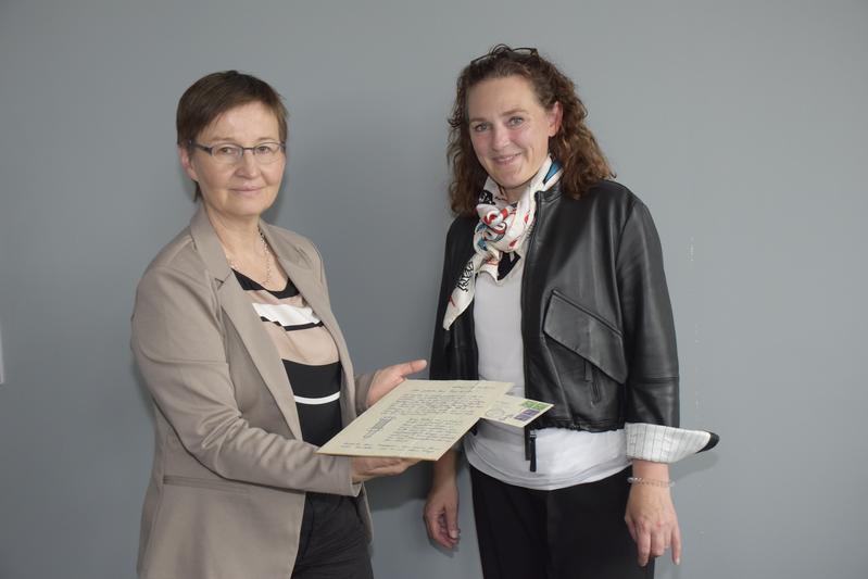 Heike Lindenschmid (rechts) übergibt das historische Dokument an Dr. Elke Koch.