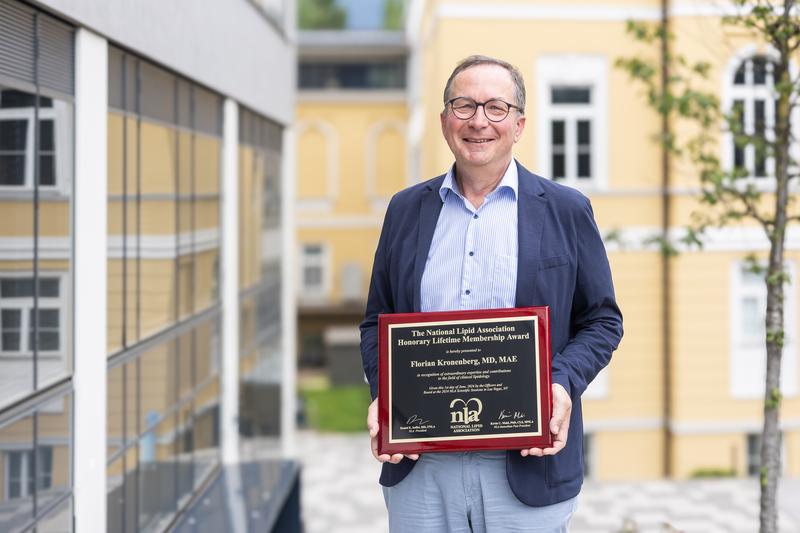 Institutsdirektor Florian Kronenberg hält die Urkunde der National Lipid Association in Händen.