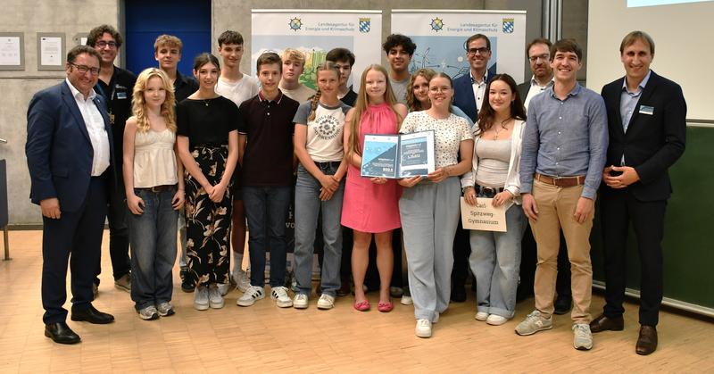 Das Siegerteam des Carl-Spitzweg Gymnasiums Germering mit Wirtschaftsstaatssekretär Tobias Gotthardt (links), Prof. Dr. Ralph Schneider, Präsident der OTH Regensburg (5. von rechts) sowie der Jury des Wasserstoff-Wettbewerbs.