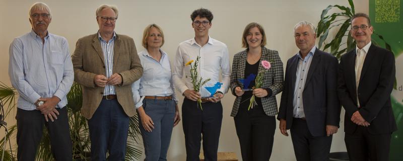 Zwei der drei Innovationspreisträger_innen 2023, Volkan Turan und Carolin Grodt, freuen sich gemeinsam mit Wolfgang Kühl, Rektor Prof. Dr. Bodo Wiegand-Hoffmeister, Dr. Meike Quaas, Bürgermeister Thomas Beyer und Kay Facklam.