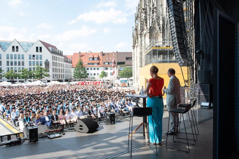 Bühne Münsterplatz: Gut gefüllt: Moderatorin Dr. Denise Burgert und Uni-Präsident Professor Michael Weber blicken von der Bühne auf den Münsterplatz (Foto: Elvira Eberhardt / Uni Ulm)